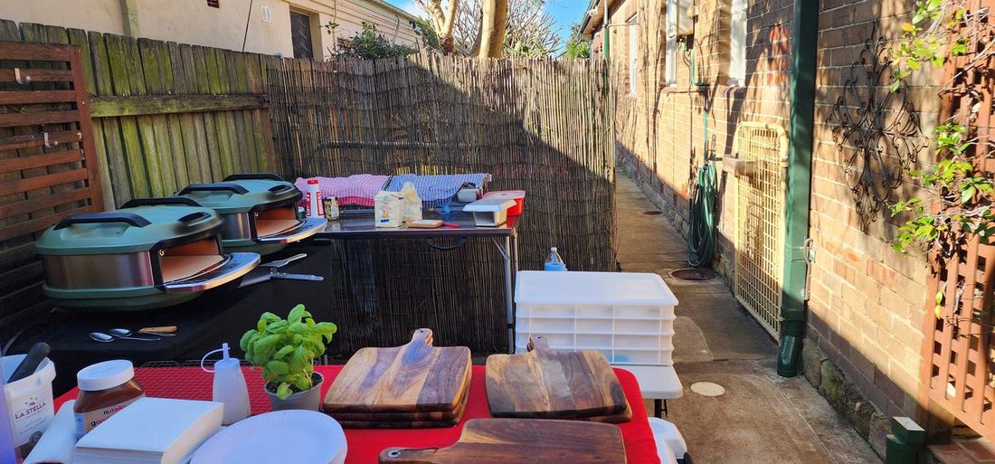 Azzurri Pizza Catering professional mobile setup — wood-fired pizza ovens, fresh basil, La Stella mozzarella, wooden cutting boards ready for a Sydney event